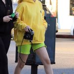 Selena Gomez Rocks a Vibrant Ensemble with Neon Sweatshirt and Biker Shorts, Capturing Moments with an Instant Camera